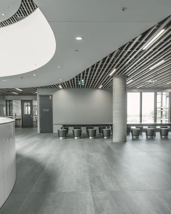 University staircase, wall cladding, and flooring featuring Laminam Pietra di Savoia Grigia porcelain; sleek grey surfaces with a structured Bocciardato finish, offering durability and modern elegance.