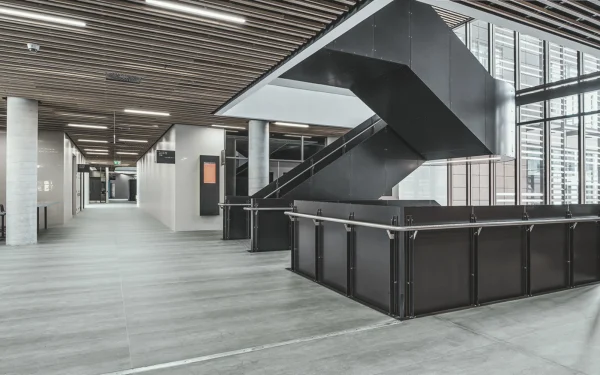 University staircase, wall cladding, and flooring featuring Laminam Pietra di Savoia Grigia porcelain; sleek grey surfaces with a structured Bocciardato finish, offering durability and modern elegance.