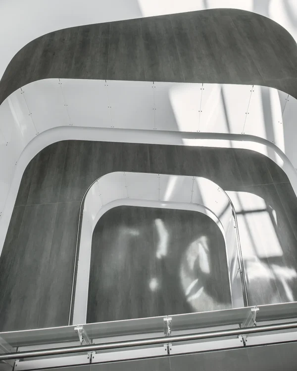 University staircase, wall cladding, and flooring featuring Laminam Pietra di Savoia Grigia porcelain; sleek grey surfaces with a structured Bocciardato finish, offering durability and modern elegance.